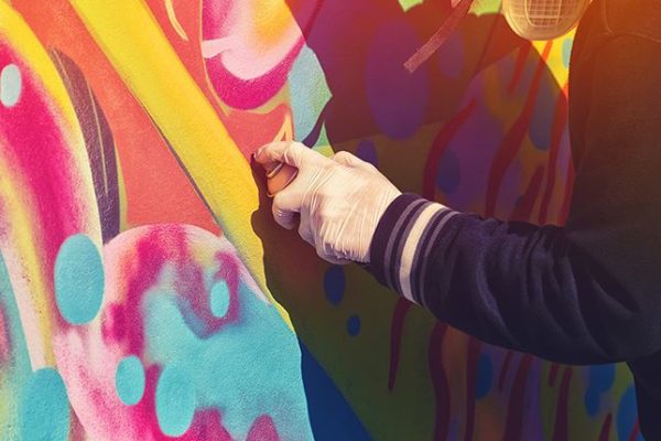 creative street artist spray-painting a mural